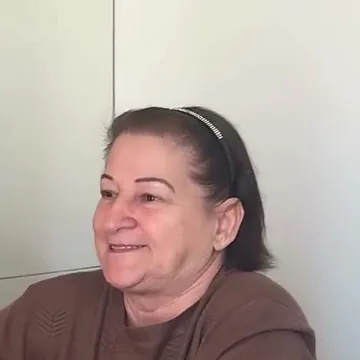 D. Lourdes, paciente de implantes, sorrindo no consultório